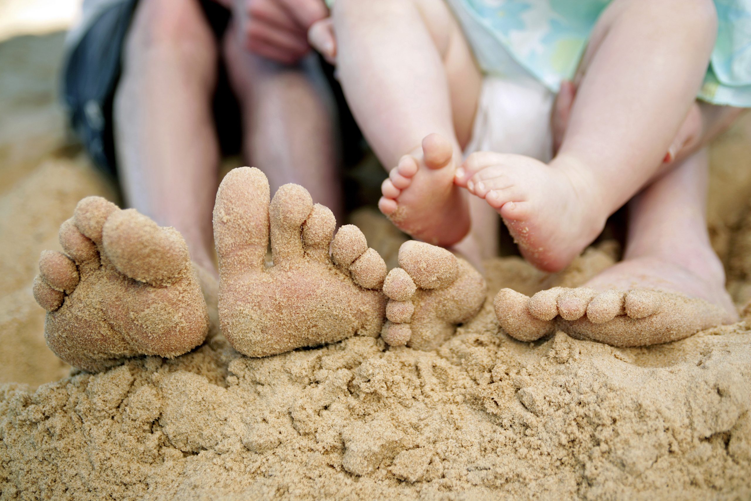 feet playing with sand on the beach